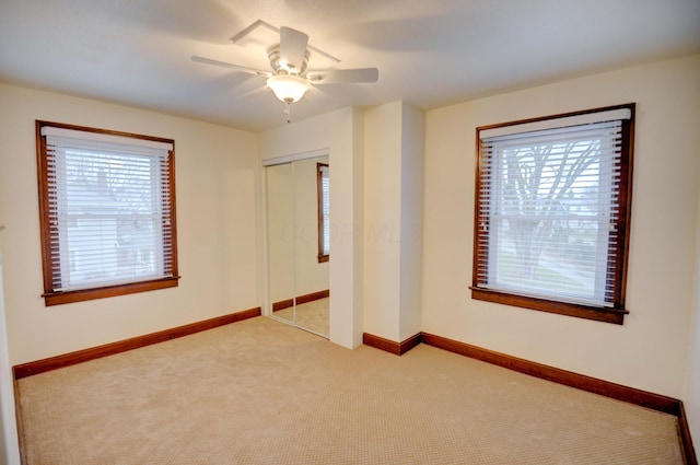 unfurnished bedroom with multiple windows, ceiling fan, a closet, and light colored carpet