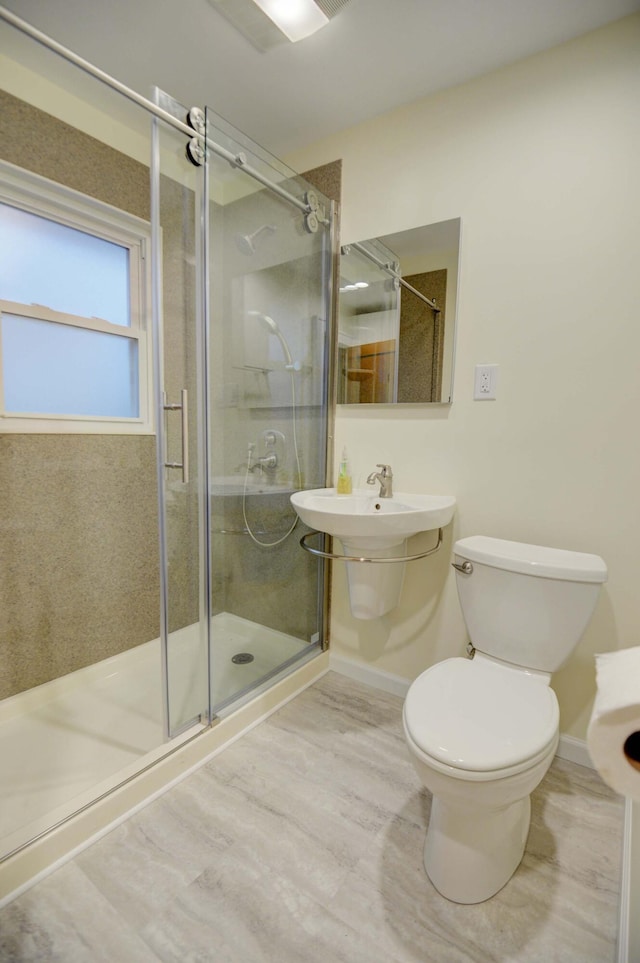 bathroom featuring toilet and a shower with door