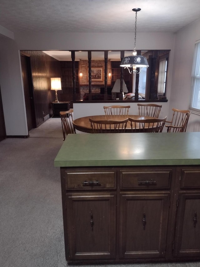 kitchen featuring decorative light fixtures, light colored carpet, and dark brown cabinetry