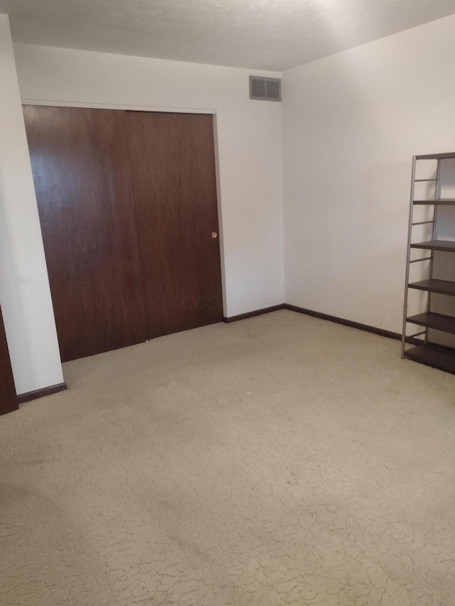 unfurnished room with a textured ceiling and light colored carpet