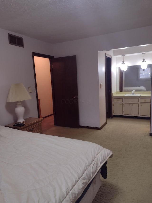 bedroom featuring ensuite bathroom, light colored carpet, and sink