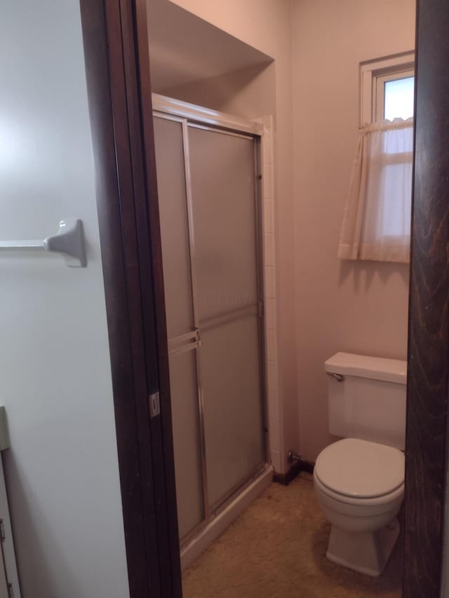 bathroom with a shower with shower door and toilet