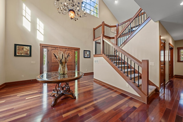 entryway featuring dark wood-type flooring, high vaulted ceiling, and a chandelier