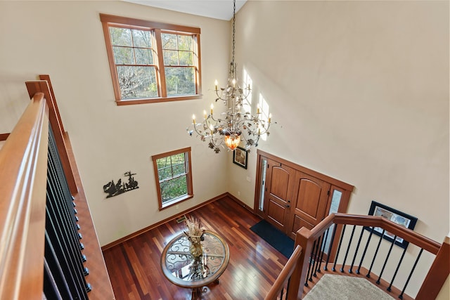 entrance foyer with a towering ceiling, dark hardwood / wood-style floors, and a notable chandelier