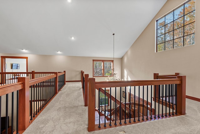 hall with carpet flooring, lofted ceiling, and a notable chandelier