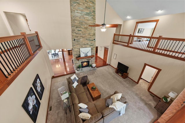 carpeted living room featuring a stone fireplace, ceiling fan, and high vaulted ceiling