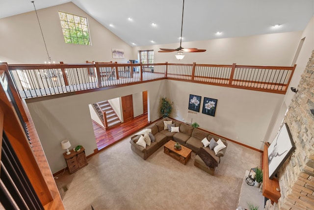 living room with light wood-type flooring, ceiling fan with notable chandelier, high vaulted ceiling, and a wealth of natural light