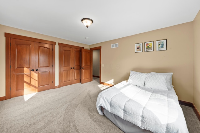 bedroom featuring carpet and two closets