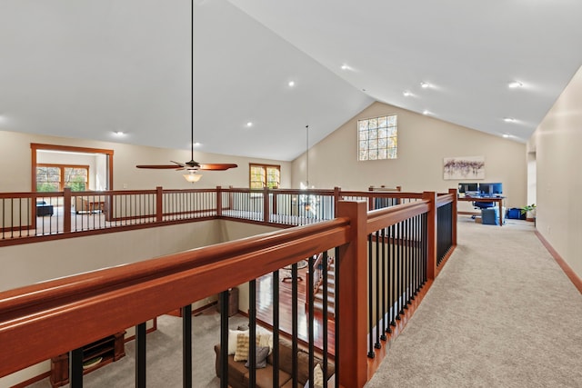 hall featuring light colored carpet, plenty of natural light, and lofted ceiling