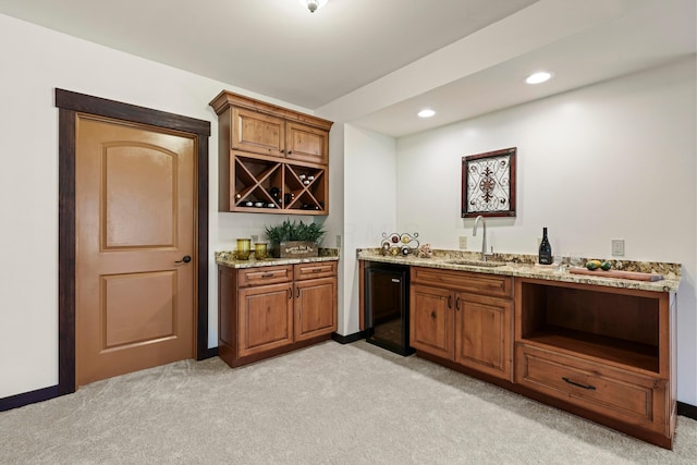 bar featuring black refrigerator, sink, light stone countertops, and light carpet