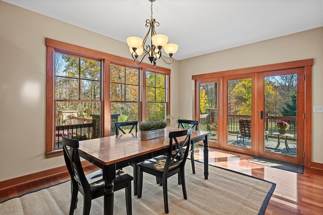 dining space with french doors, light hardwood / wood-style floors, and an inviting chandelier