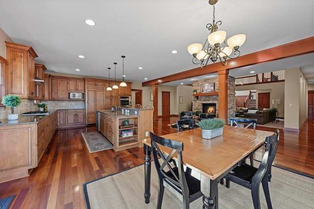 dining area with dark hardwood / wood-style flooring, decorative columns, sink, a fireplace, and a chandelier