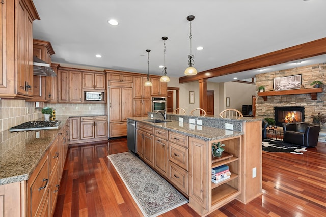 kitchen with a spacious island, sink, a fireplace, dark hardwood / wood-style flooring, and stainless steel appliances