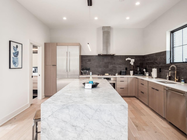 kitchen with sink, wall chimney exhaust hood, stainless steel appliances, and light hardwood / wood-style floors