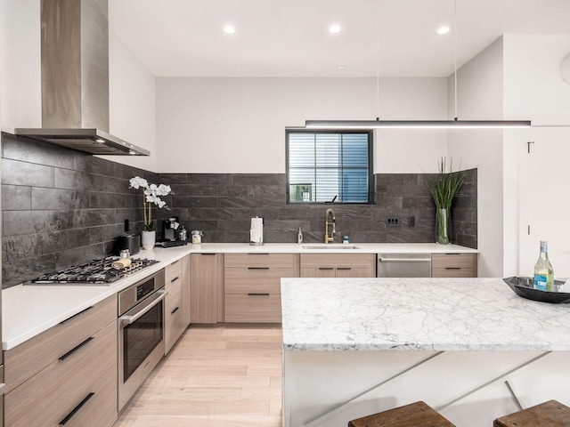 kitchen with appliances with stainless steel finishes, light wood-type flooring, tasteful backsplash, and wall chimney exhaust hood