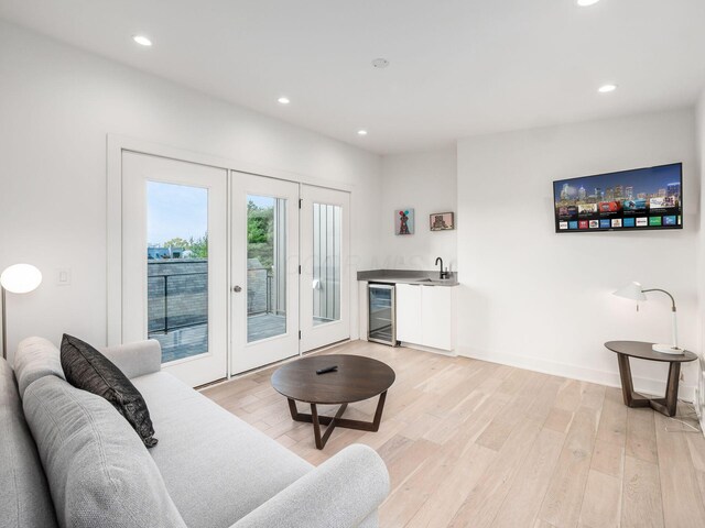 living room featuring french doors, beverage cooler, indoor wet bar, and light hardwood / wood-style floors