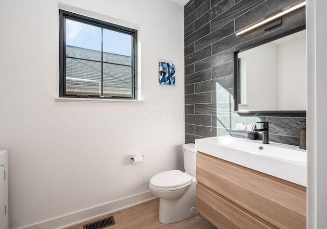 bathroom featuring hardwood / wood-style floors, vanity, backsplash, toilet, and tile walls