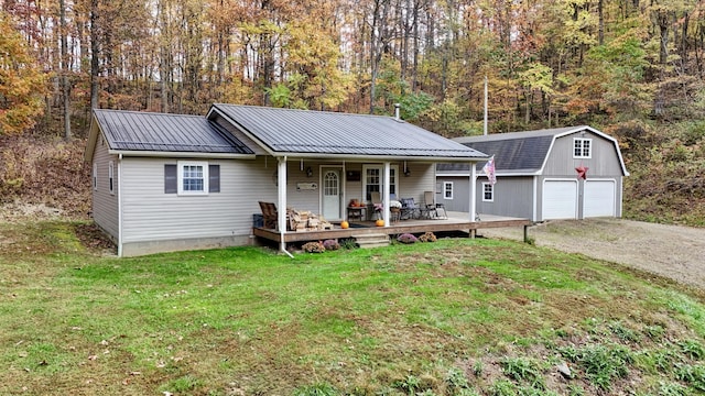 view of front of house with an outbuilding, covered porch, a front yard, and a garage