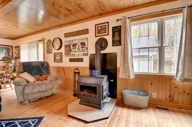 living room with hardwood / wood-style floors, wood walls, a wood stove, and wooden ceiling