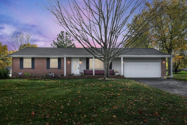 ranch-style home with driveway, an attached garage, a front lawn, and brick siding