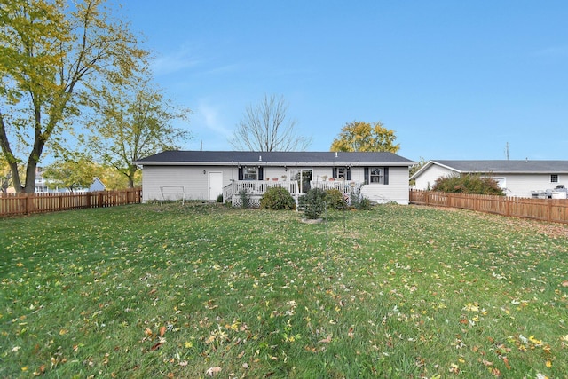 back of property with a fenced backyard, a lawn, and a wooden deck