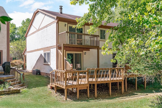 back of property featuring a yard, a deck, and stucco siding