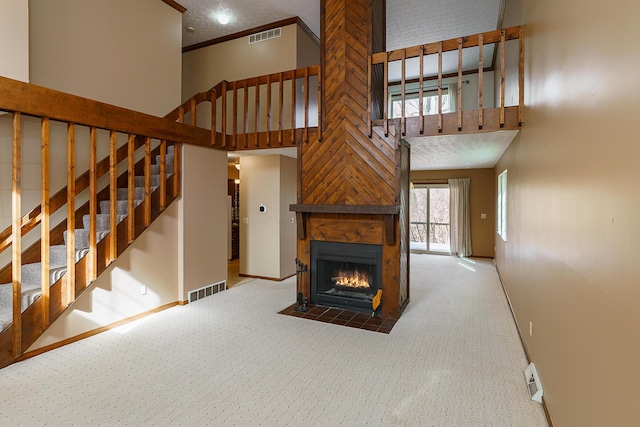 unfurnished living room with a fireplace with flush hearth, stairway, a towering ceiling, and visible vents