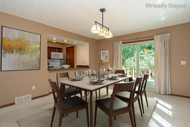 dining space with visible vents, a textured ceiling, and baseboards