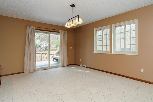 unfurnished room with a textured ceiling, carpet flooring, visible vents, and baseboards