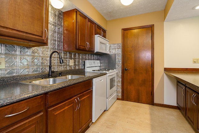 kitchen with a textured ceiling, white appliances, a sink, decorative backsplash, and dark countertops