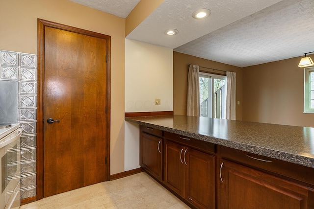 kitchen featuring a textured ceiling, recessed lighting, dark countertops, and baseboards