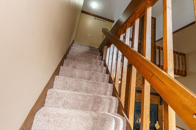 stairway featuring baseboards, visible vents, and crown molding