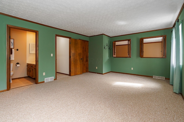 unfurnished bedroom with visible vents, light colored carpet, a textured ceiling, and ornamental molding