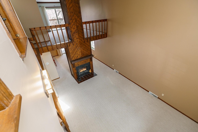 stairway with carpet, a fireplace with flush hearth, visible vents, and baseboards