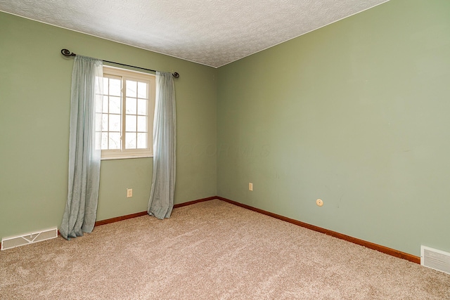 empty room featuring visible vents, light carpet, baseboards, and a textured ceiling