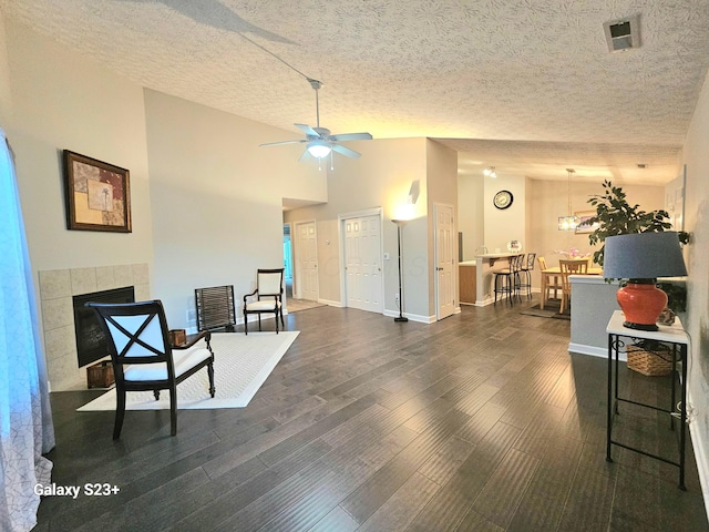 sitting room featuring ceiling fan, a fireplace, dark wood-type flooring, and a textured ceiling