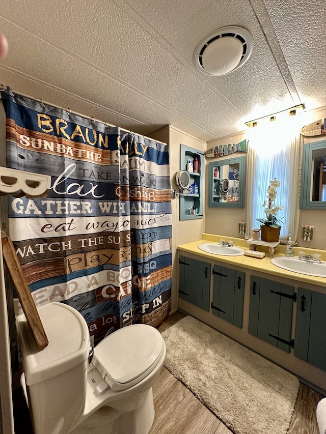 bathroom featuring vanity, a textured ceiling, hardwood / wood-style flooring, and toilet