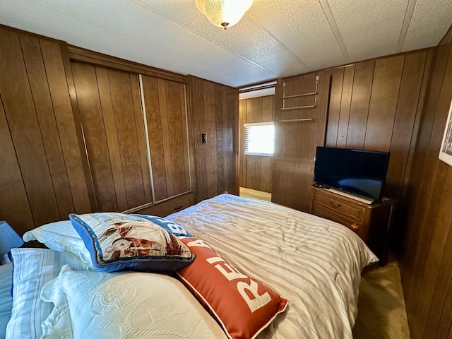 carpeted bedroom with wood walls and a textured ceiling