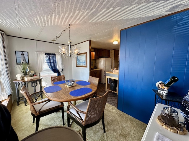 dining space with light carpet, wood walls, a textured ceiling, and an inviting chandelier