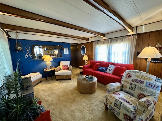 living room with beam ceiling, wooden walls, carpet flooring, and a textured ceiling