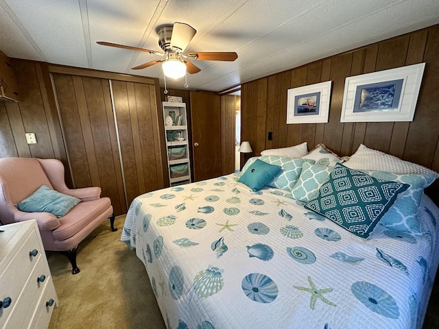 bedroom featuring ceiling fan, a closet, light colored carpet, and wood walls