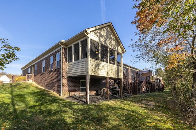 back of property featuring a patio, a lawn, and a sunroom