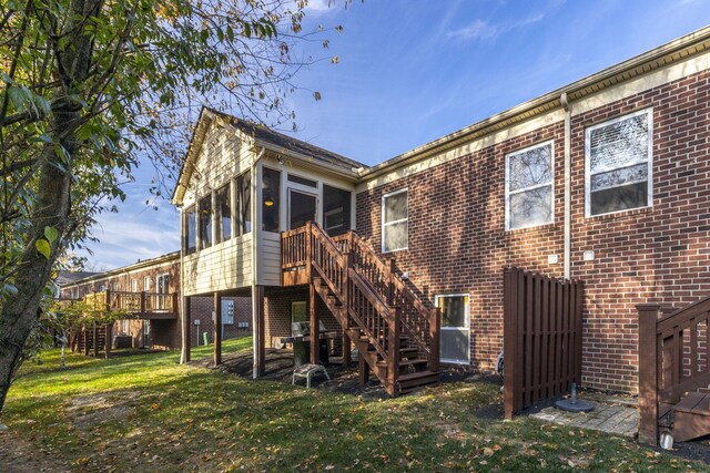 back of property with a sunroom, a yard, and a deck