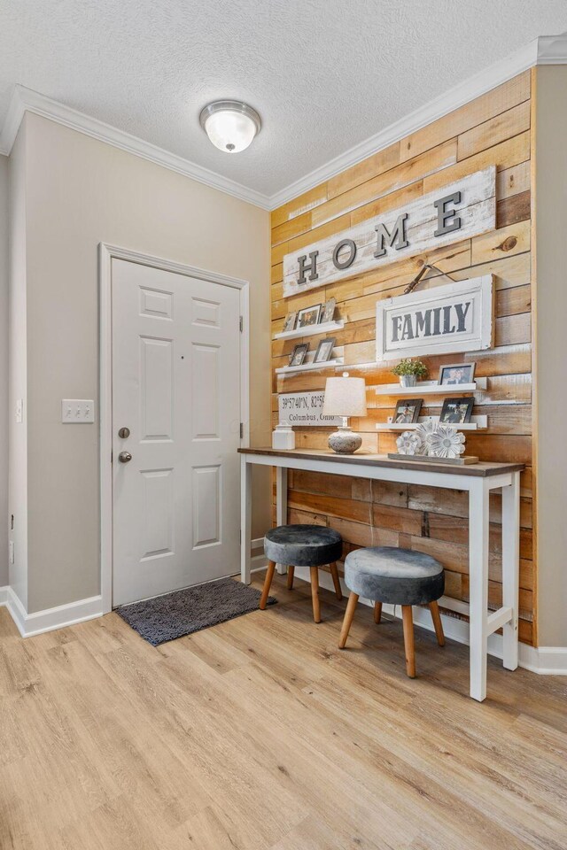 entryway featuring hardwood / wood-style floors, crown molding, and wood walls