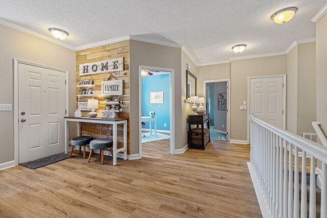 entrance foyer with a textured ceiling, light hardwood / wood-style floors, and crown molding