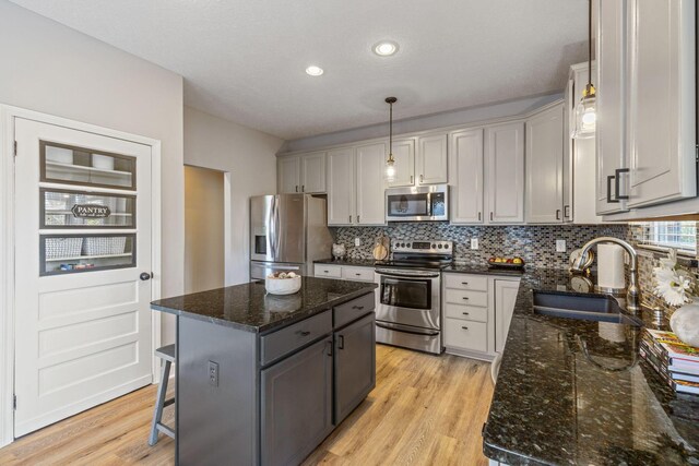 kitchen with sink, a center island, stainless steel appliances, light hardwood / wood-style flooring, and pendant lighting