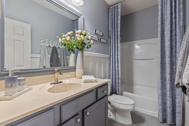 full bathroom with tile patterned flooring, vanity, shower / tub combo, and toilet