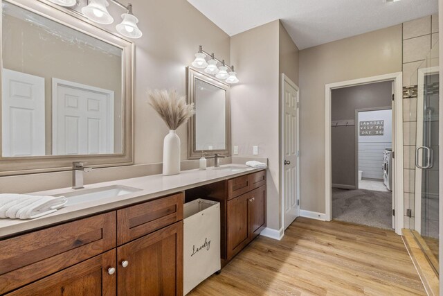 bathroom with a textured ceiling, vanity, wood-type flooring, and an enclosed shower