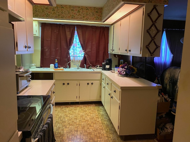 kitchen featuring white cabinets, white fridge, black electric range oven, and sink