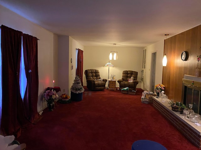 sitting room with wooden walls, a fireplace, carpet floors, and an inviting chandelier